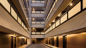 Un vestíbulo de hotel moderno con un espacio central abierto, varios ascensores y piso de madera.