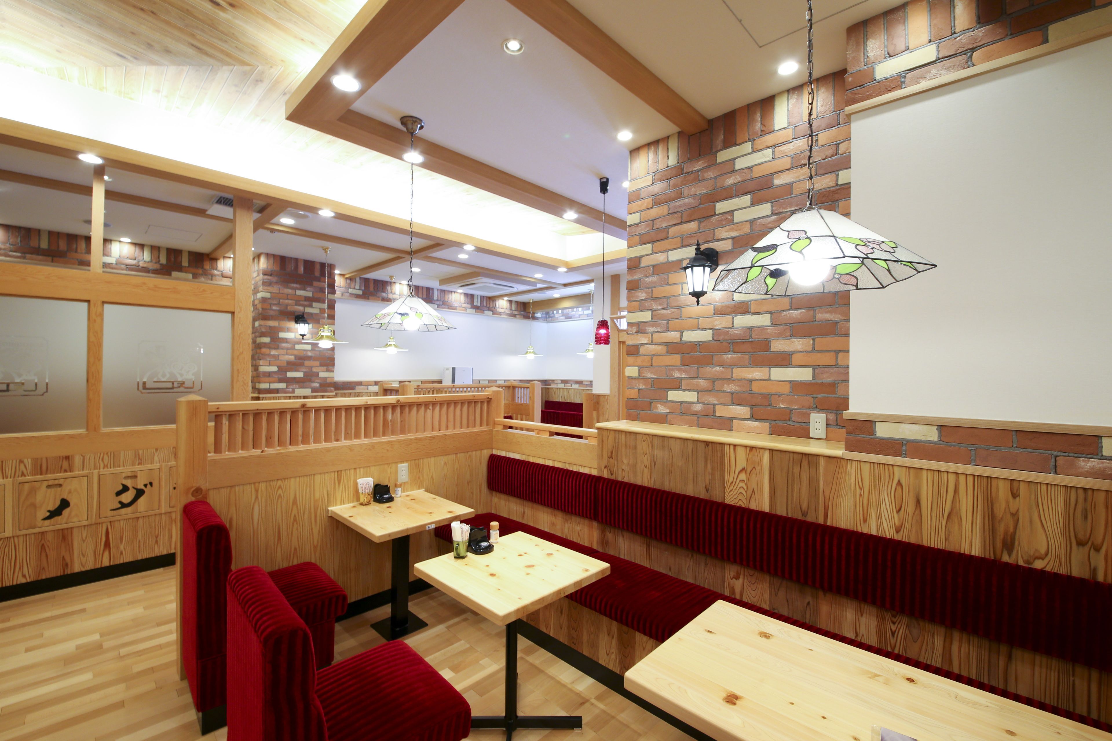 A restaurant with wooden booths, tables, and hanging lamps.