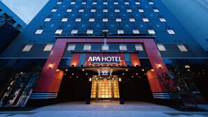 Un hotel moderno con una entrada destacada, ventanas amplias y fachada azul y roja.