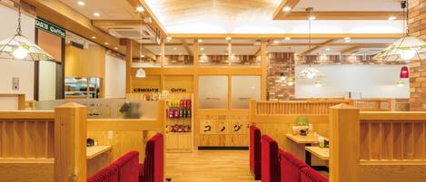A restaurant with wooden booths, a coffee station, and a brick wall.