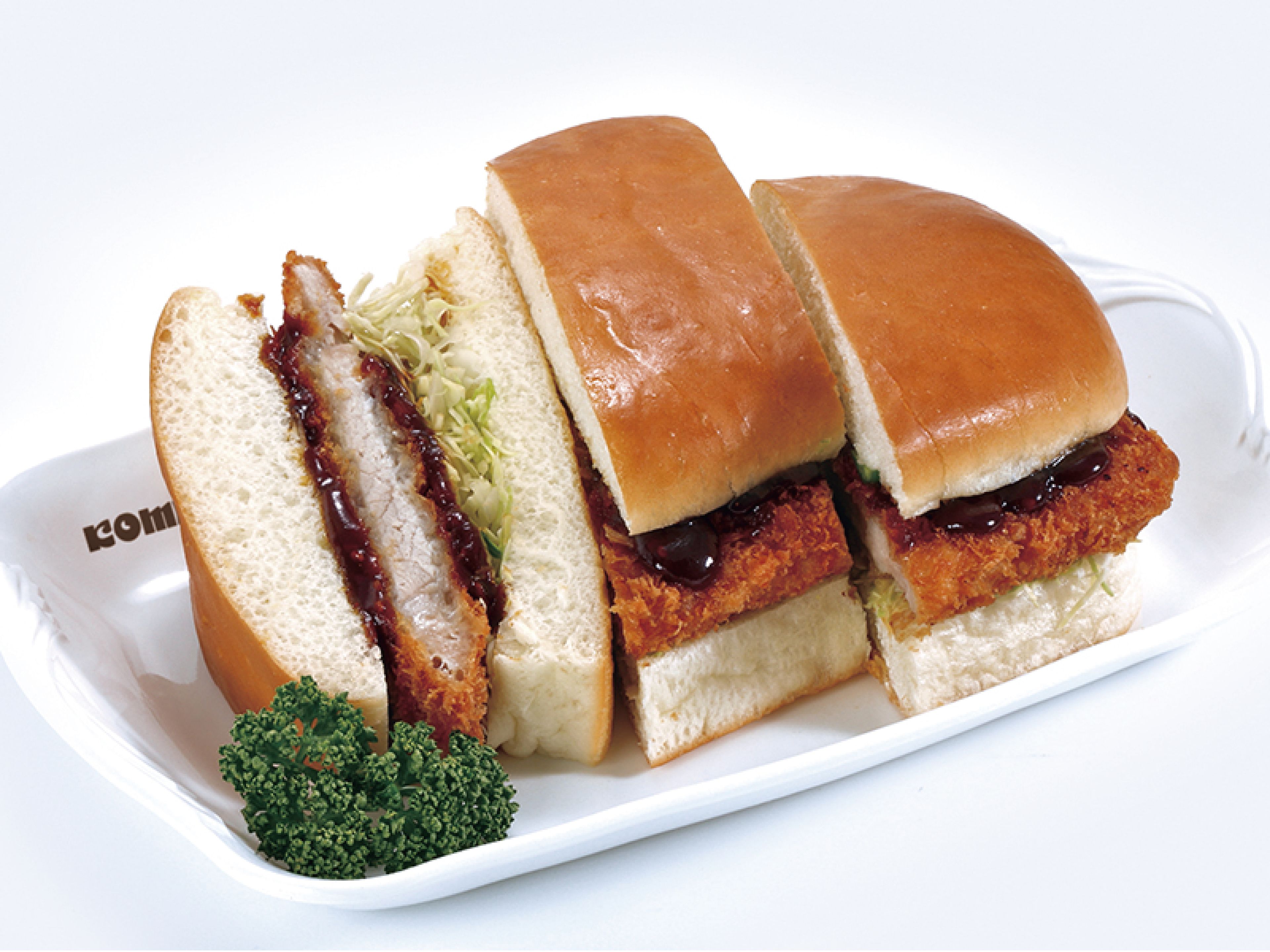A sandwich with bread, meat, and vegetables on a white plate.