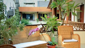 A covered outdoor seating area with wicker furniture and potted plants.