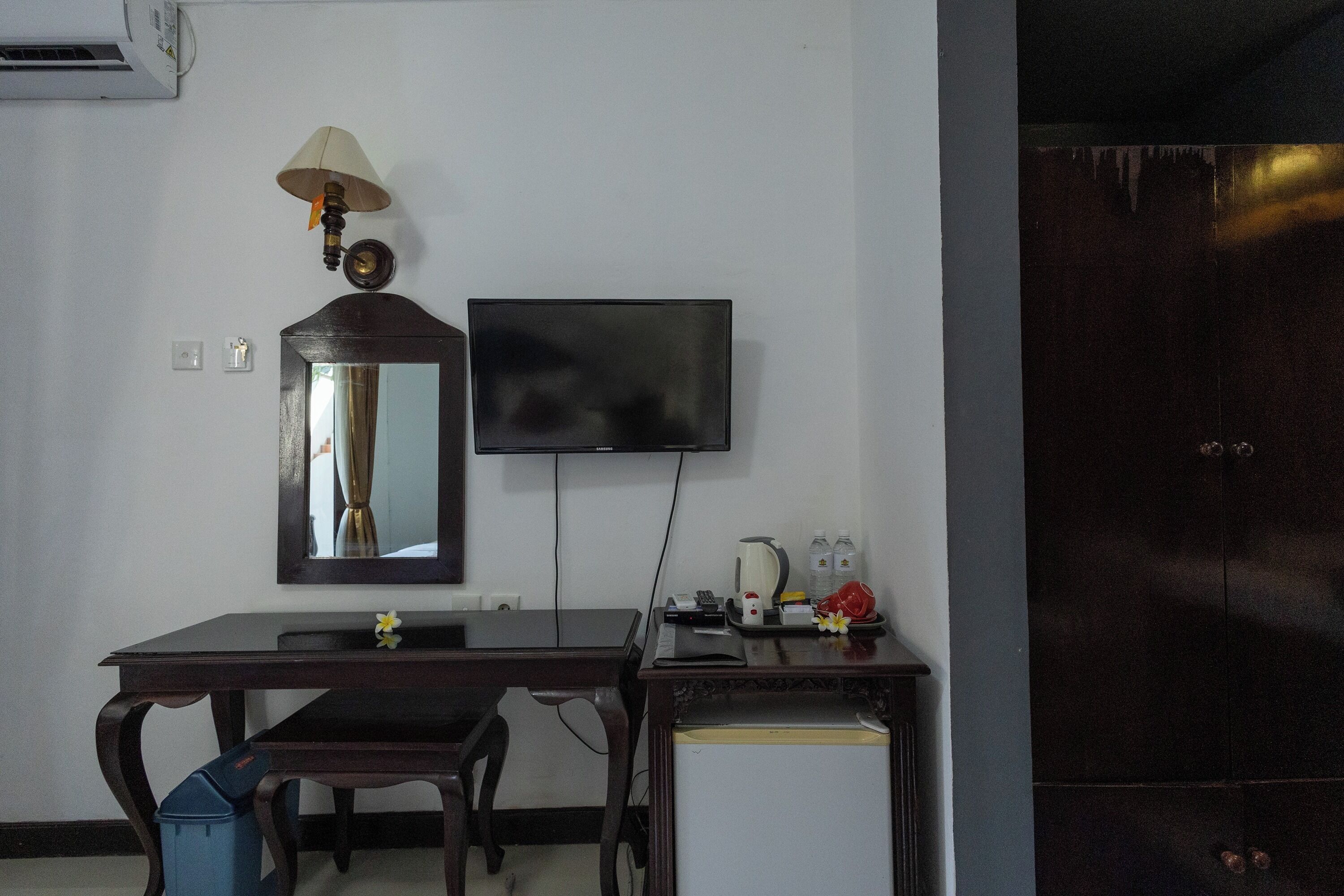 Una habitación con escritorio, silla, espejo, televisor y armario.