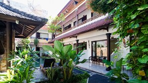 A courtyard with a pool, surrounded by lush greenery and traditional architecture.