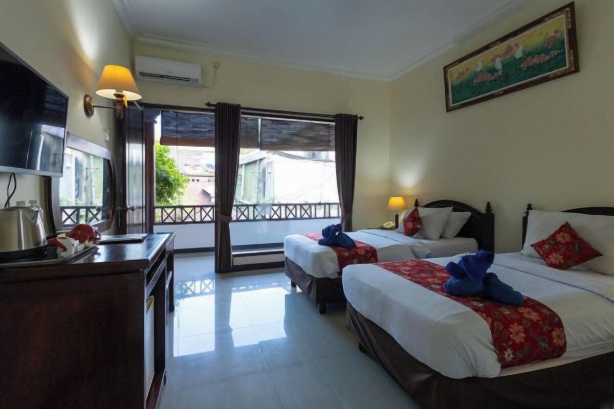 A hotel room with two beds, a TV, a desk, and a balcony with a view.