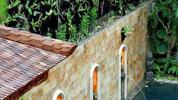 A swimming pool with a stone wall and arched openings.