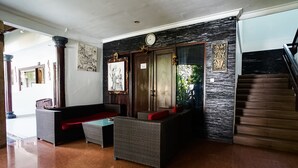 A lobby with wicker furniture, a clock, and a staircase.