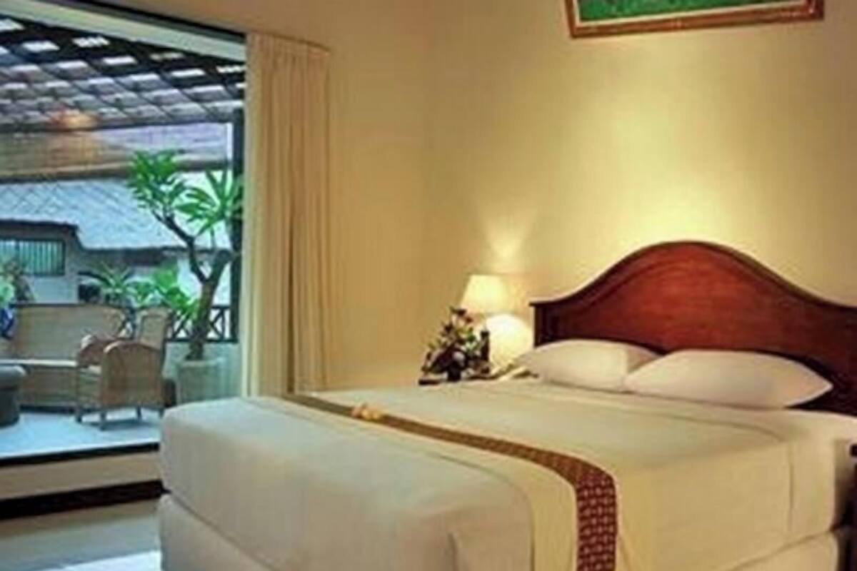 Een hotelkamer met een bed, nachtkastje, lamp en uitzicht.