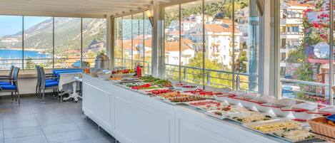 Un bufé con diversas opciones de comida y vistas al mar y a edificios.