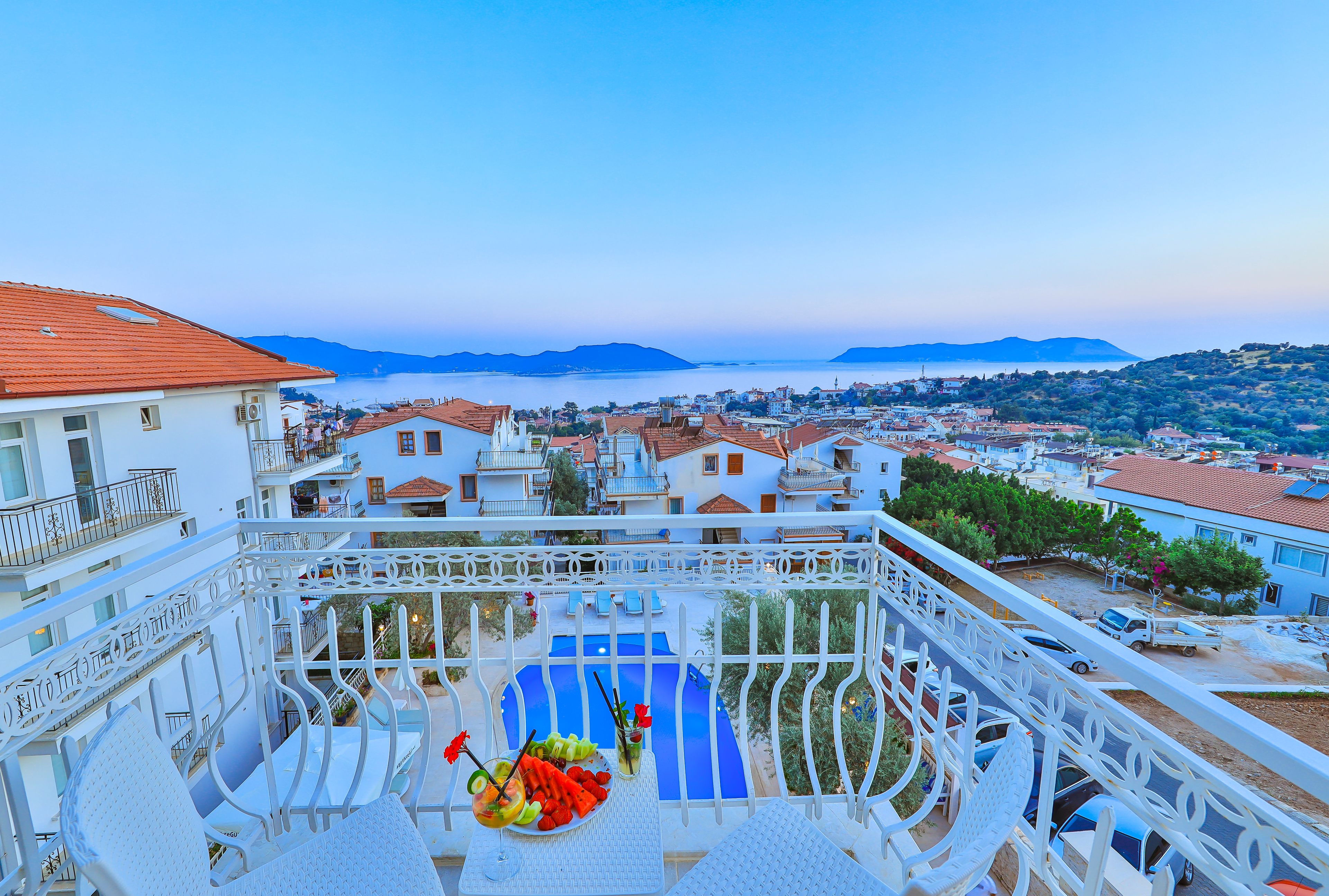 Un balcon avec une piscine, des balustrades blanches et une vue sur une ville côtière.