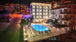 A hotel with a swimming pool, outdoor seating, and a well-lit facade. - Kas Artemis Hotel (Kas)