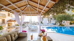 A poolside area with a covered seating area, a pool, and a view of the surrounding buildings. - Kas Artemis Hotel (Kas)