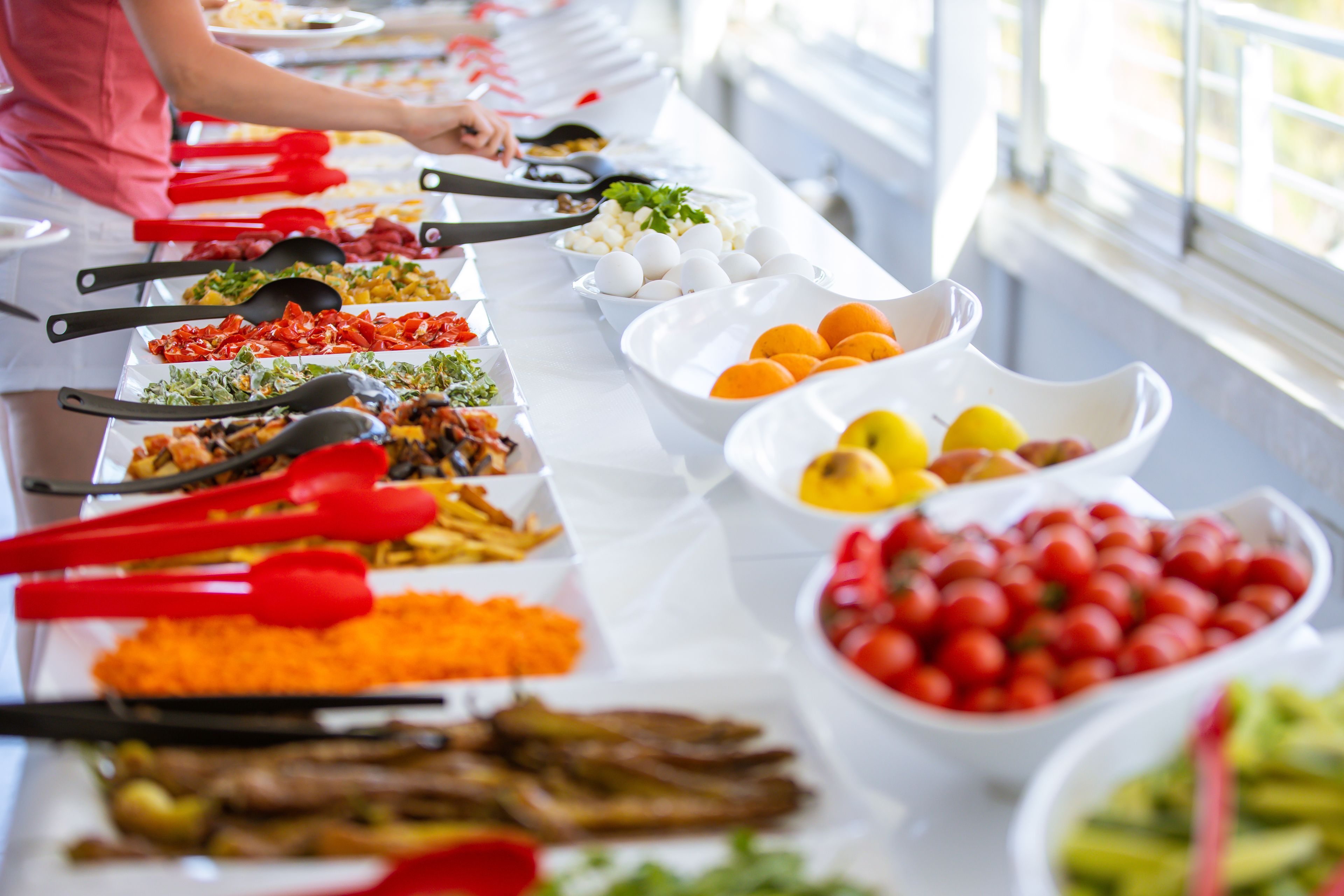 A buffet table with various food items and utensils.