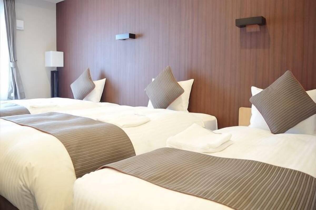 A hotel room with two beds, a wooden headboard, and a nightstand with a lamp.