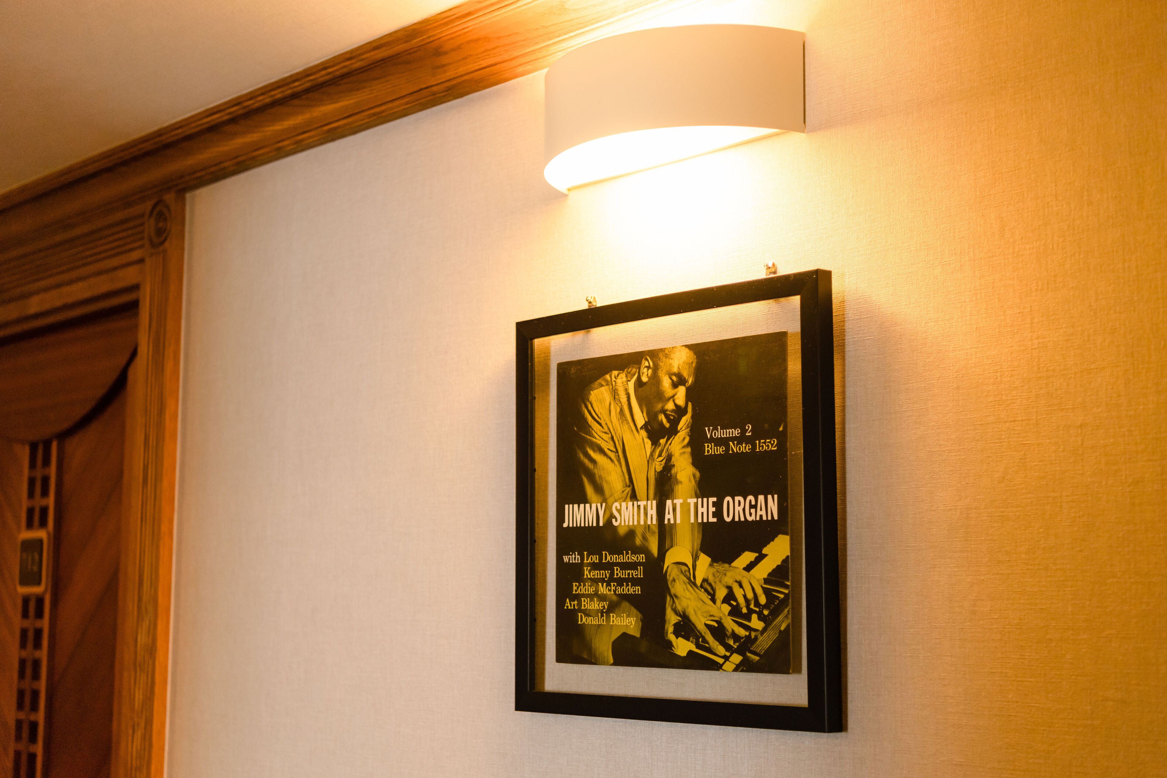 A framed poster on a wall with a light fixture above it.