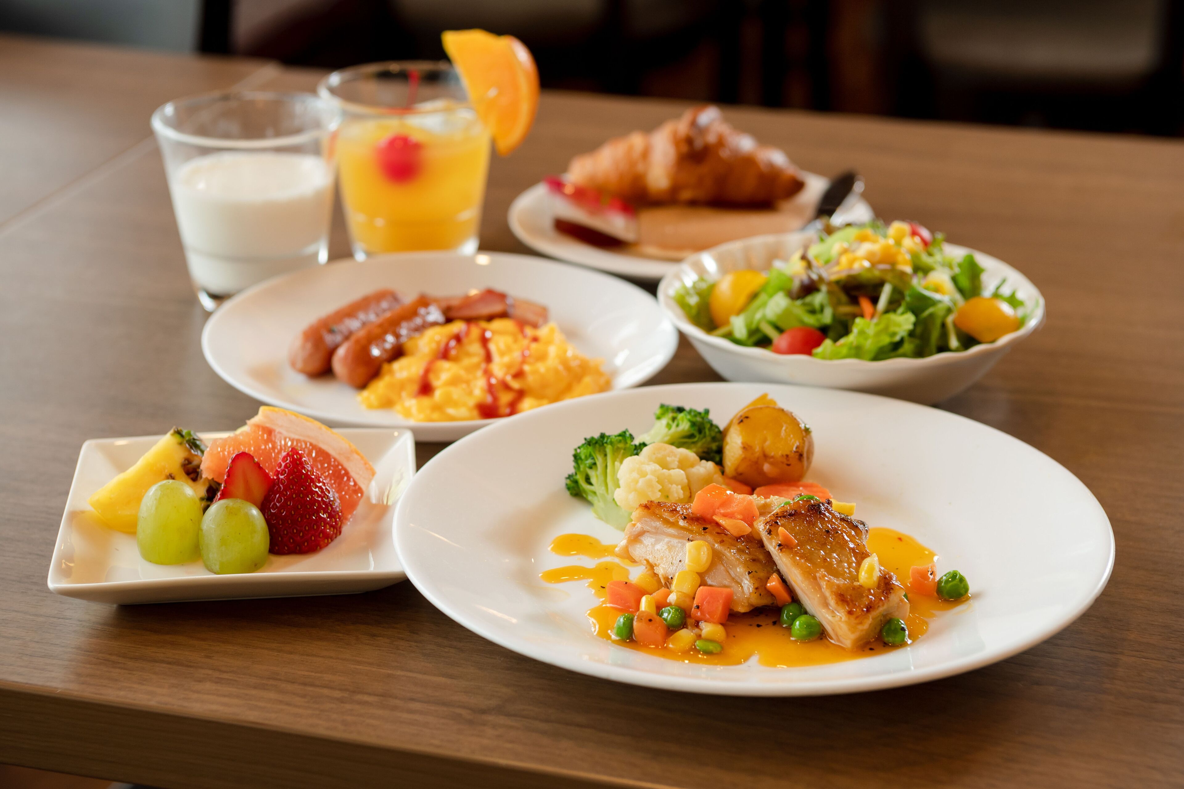 A table with various dishes including a plate of fish, a bowl of salad, and a plate with sausages and eggs.