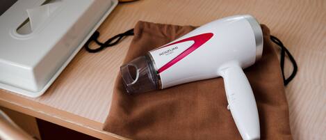 A hair dryer on a wooden table with a tissue box and a brown cloth.