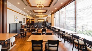 A spacious restaurant with wooden tables and chairs, large windows with blinds, and a chandelier. - HOTEL AZAT Naha (Naha)