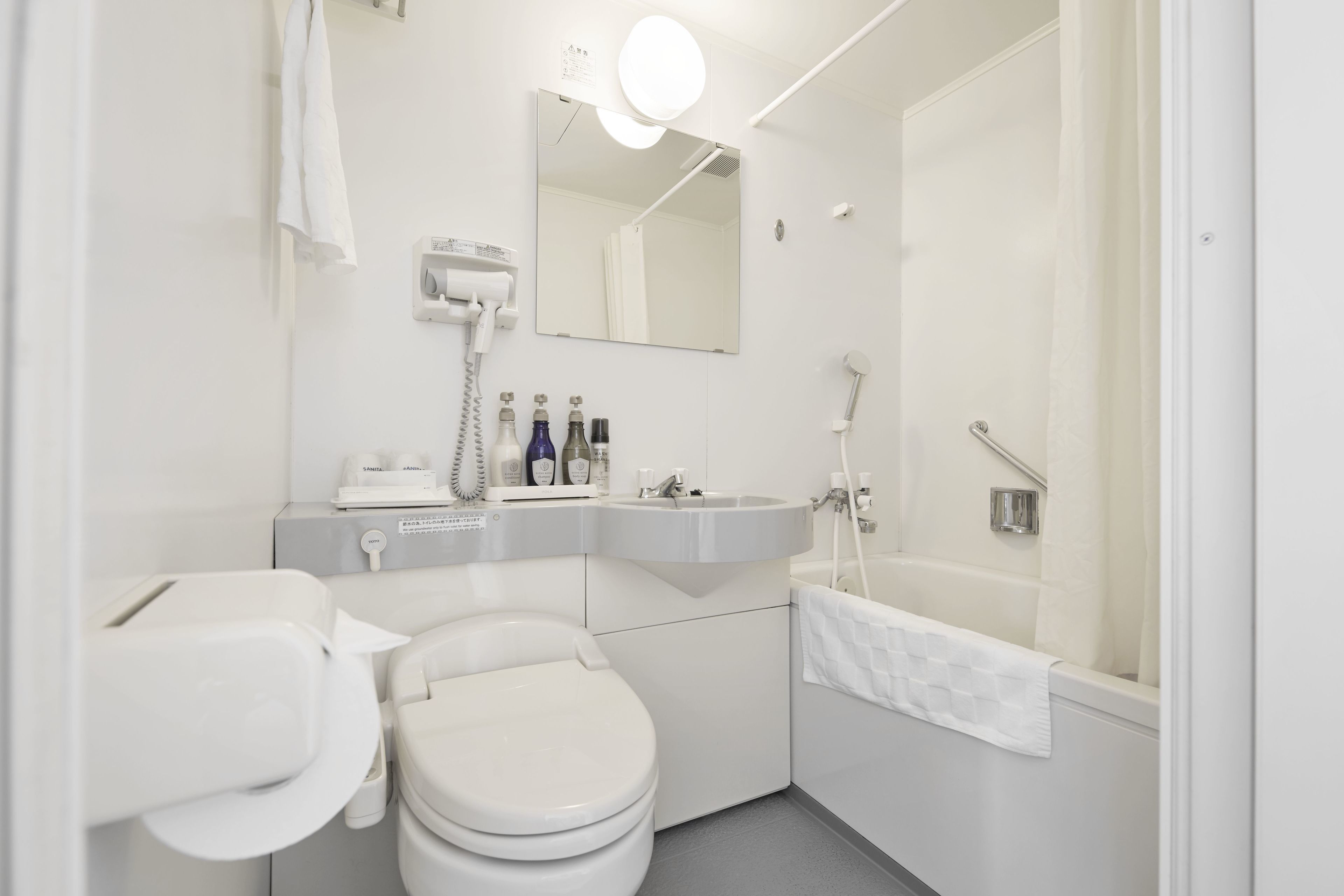 A modern bathroom with a toilet, sink, mirror, and shower.