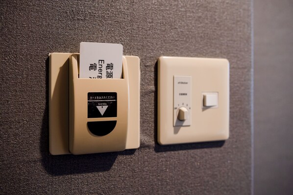 A wall-mounted card reader with a card inserted, next to a light switch. - HOTEL AZAT Naha (Naha)