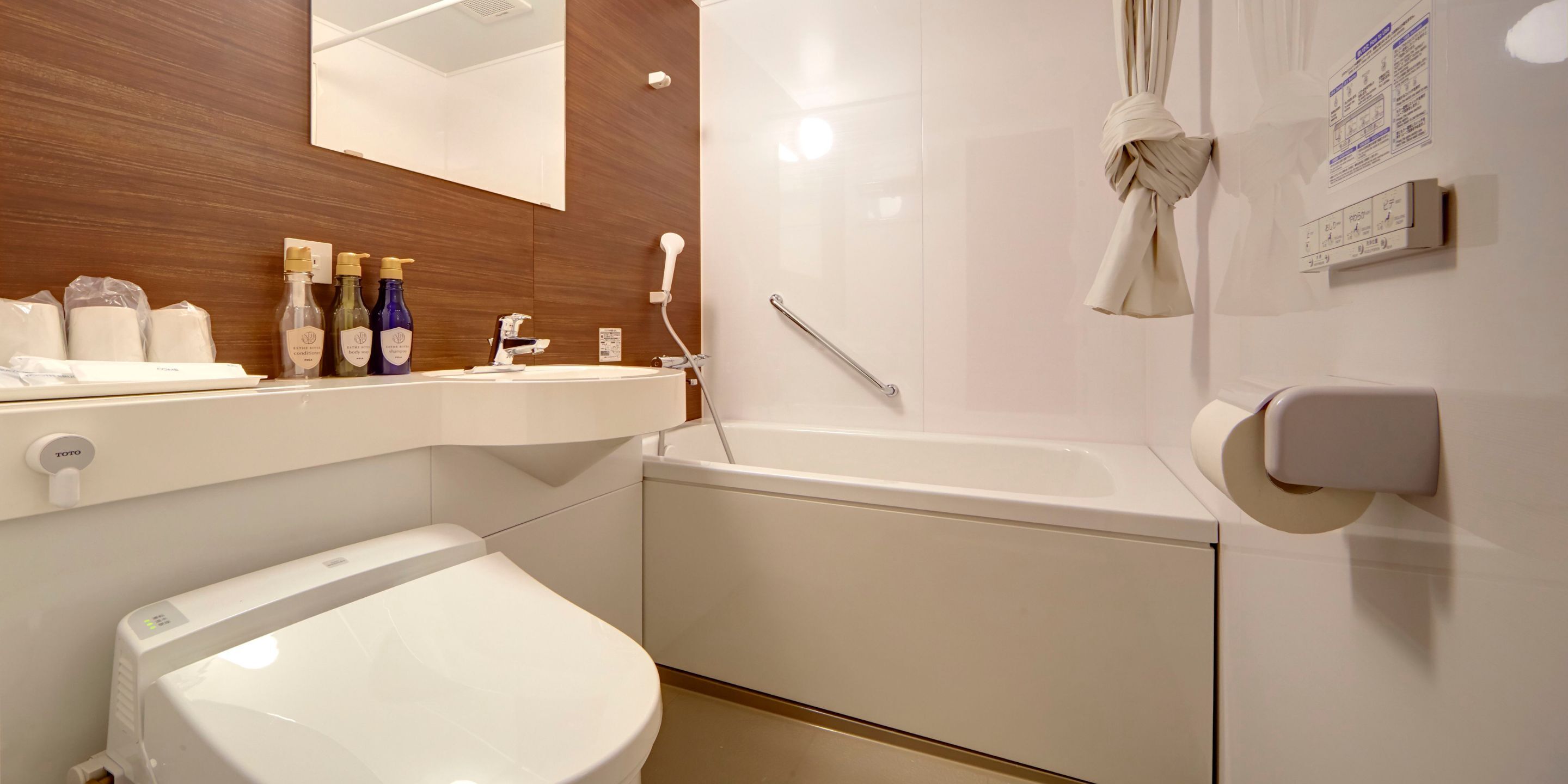 Une salle de bain moderne avec des toilettes blanches, un lavabo avec des articles de toilette et une baignoire.