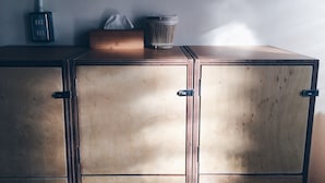 A wooden cabinet with two doors, a tissue box, and a trash bin on top. - Altrove House - Hostel (Hengchun)