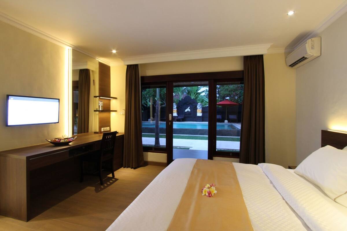 A hotel room with a bed, desk, and a TV.