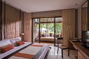 Relax in a spacious room with a large bed, desk, and balcony offering a view of lush greenery.