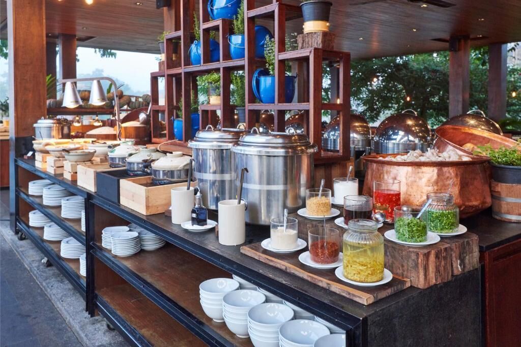 Un buffet composé de différents récipients contenant des aliments, de plats de service et d’ustensiles.