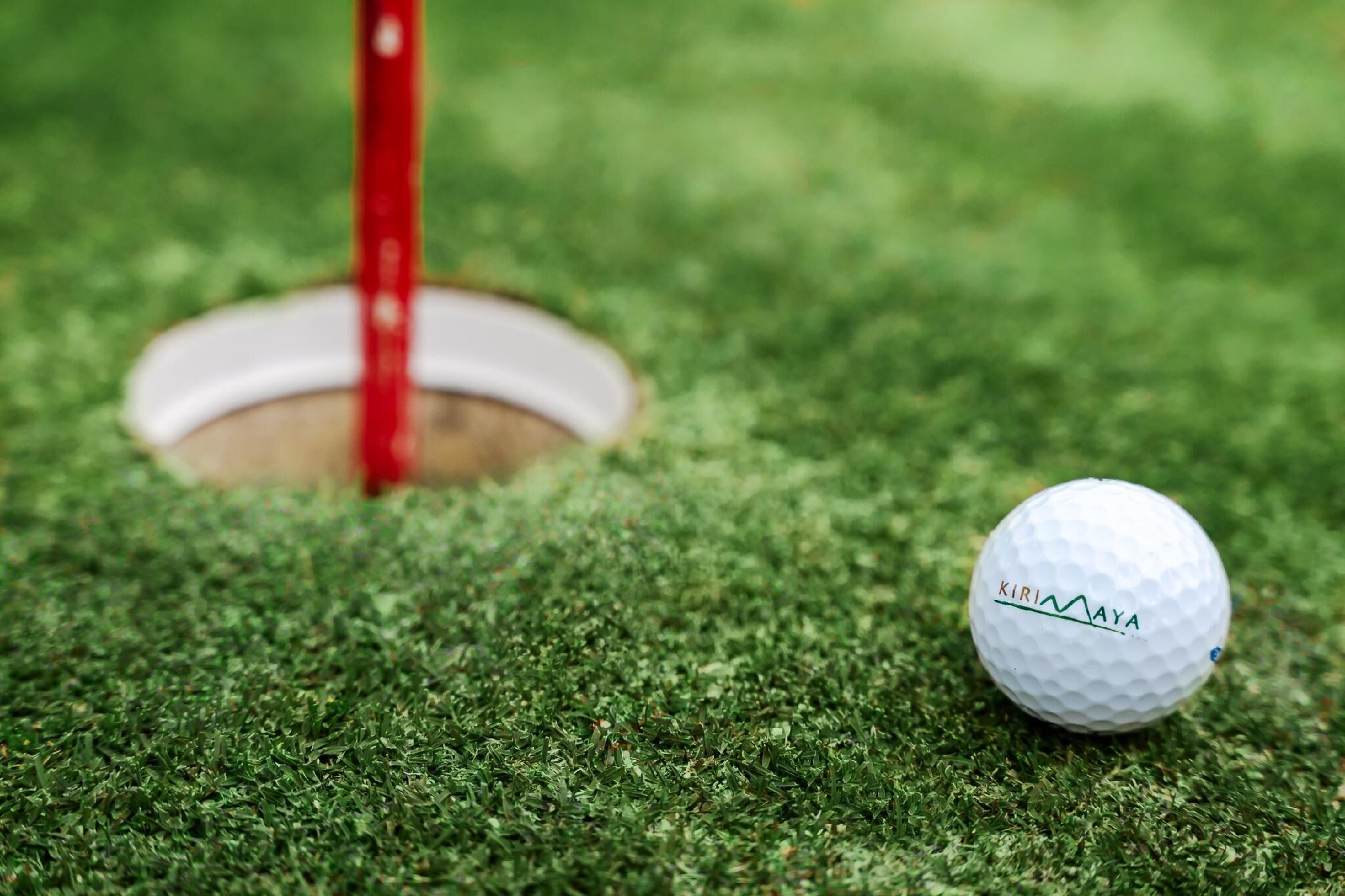 Une balle de golf sur un gazon vert, avec un trou à proximité.