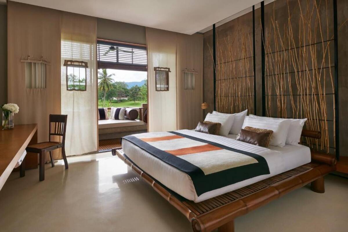 A bedroom with a large bed, a desk, and a view of the outdoors.