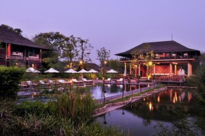 Relax by the tranquil pool surrounded by lush greenery and lounge under the shade of umbrellas.