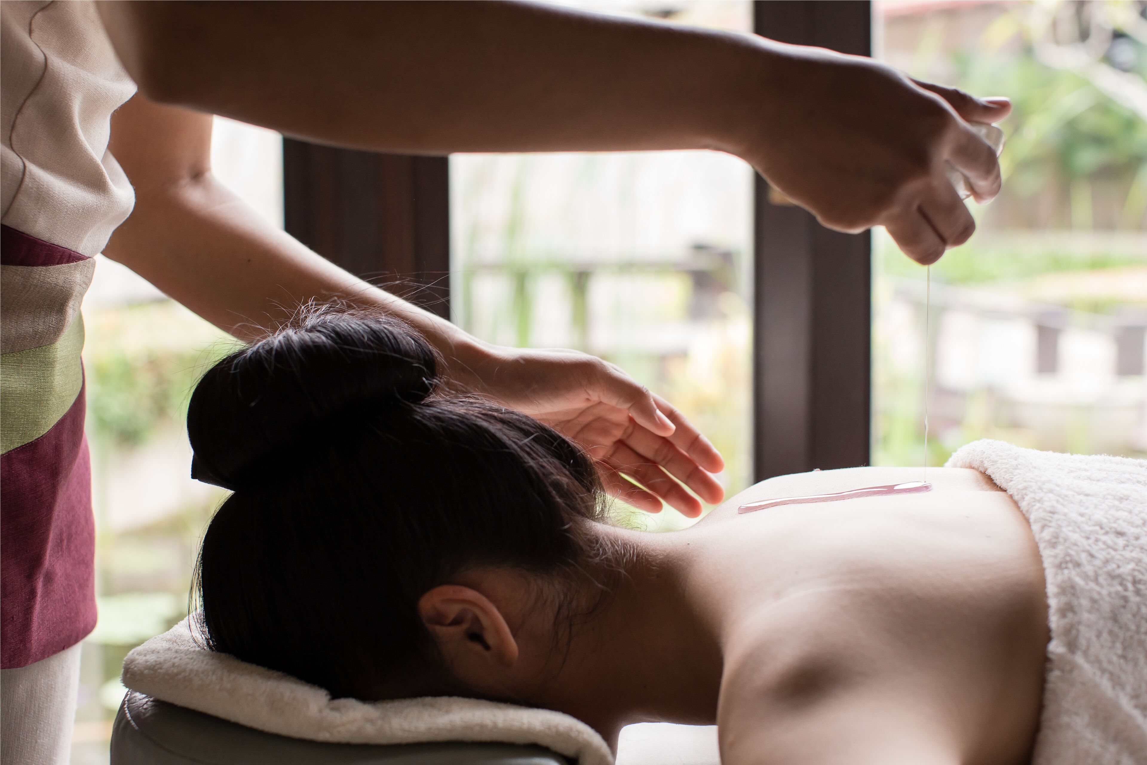 A person receiving a massage with a towel wrapped around their head.