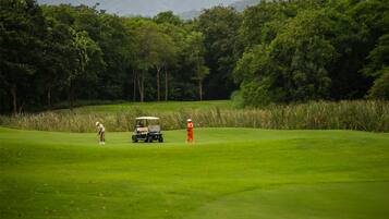 Un campo de golf con un carrito y dos jugadores.