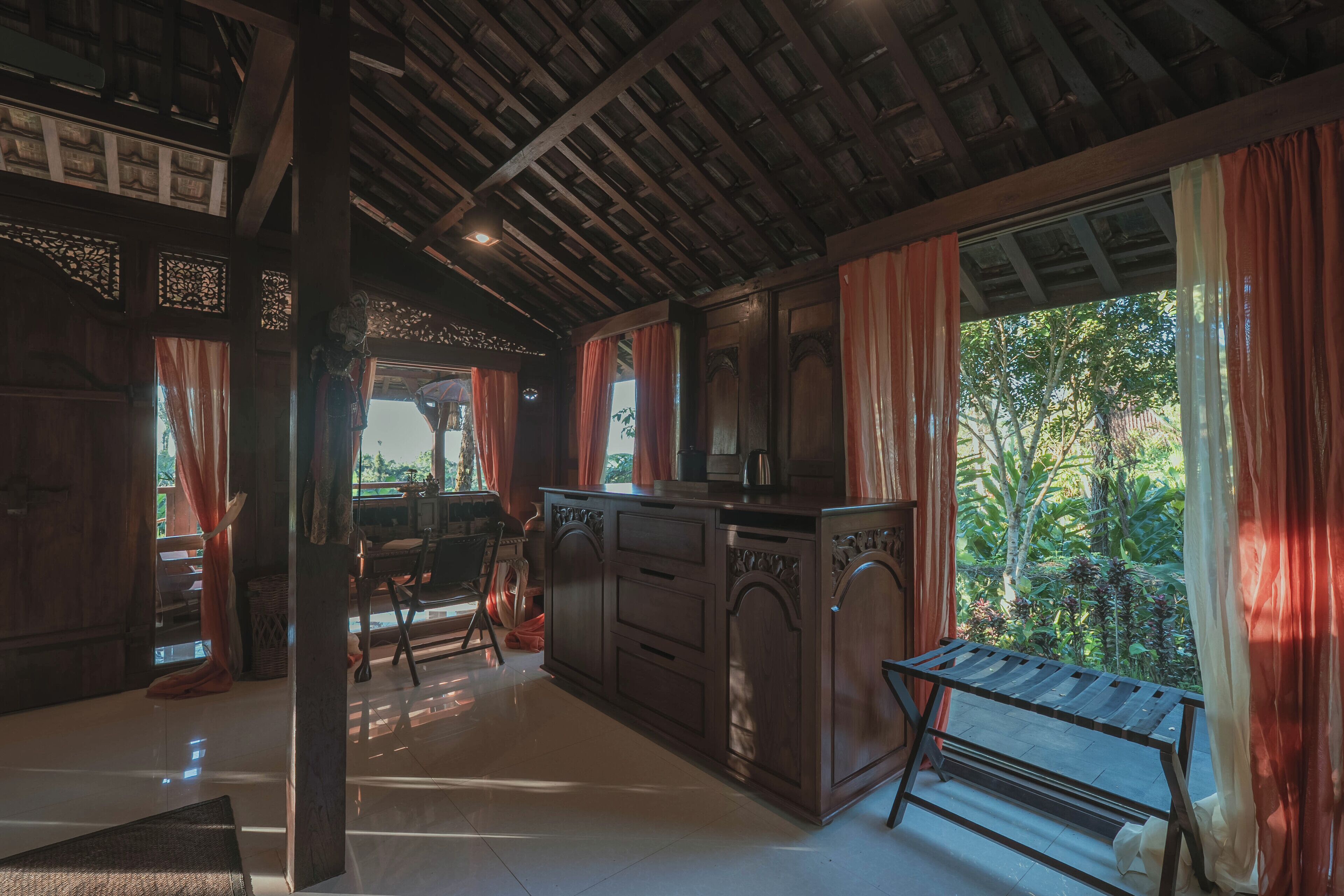 Una cocina amplia con techo de madera, ventanas grandes con cortinas y vistas a zonas verdes.