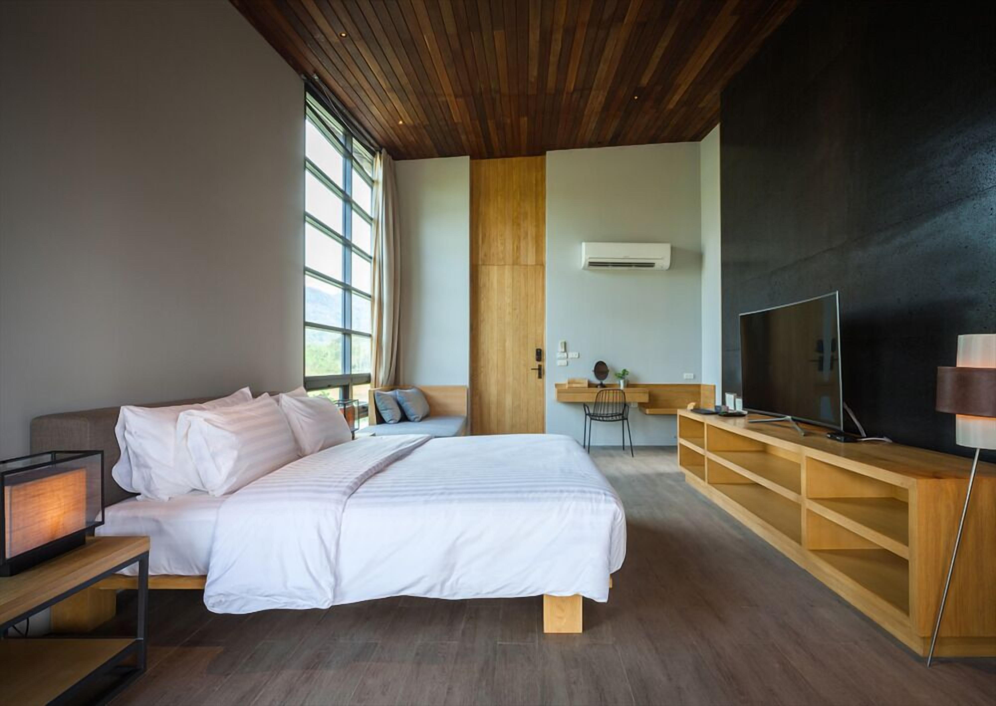 Une chambre moderne avec un grand lit, un bureau, une télévision et une fenêtre.