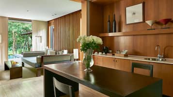 A modern kitchen with wooden cabinets, a dining table, and a vase of white flowers.