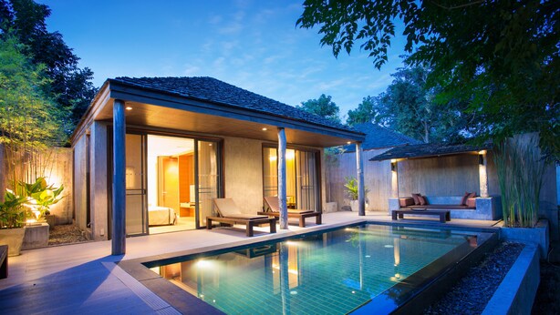 A modern outdoor pool area with a covered seating area, lounge chairs, and a well-lit patio. - MUTHI MAYA Forest Pool Villa Resort (Pak Chong)