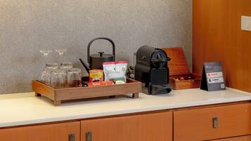 A coffee station with a kettle, coffee machine, and various coffee products on a countertop.