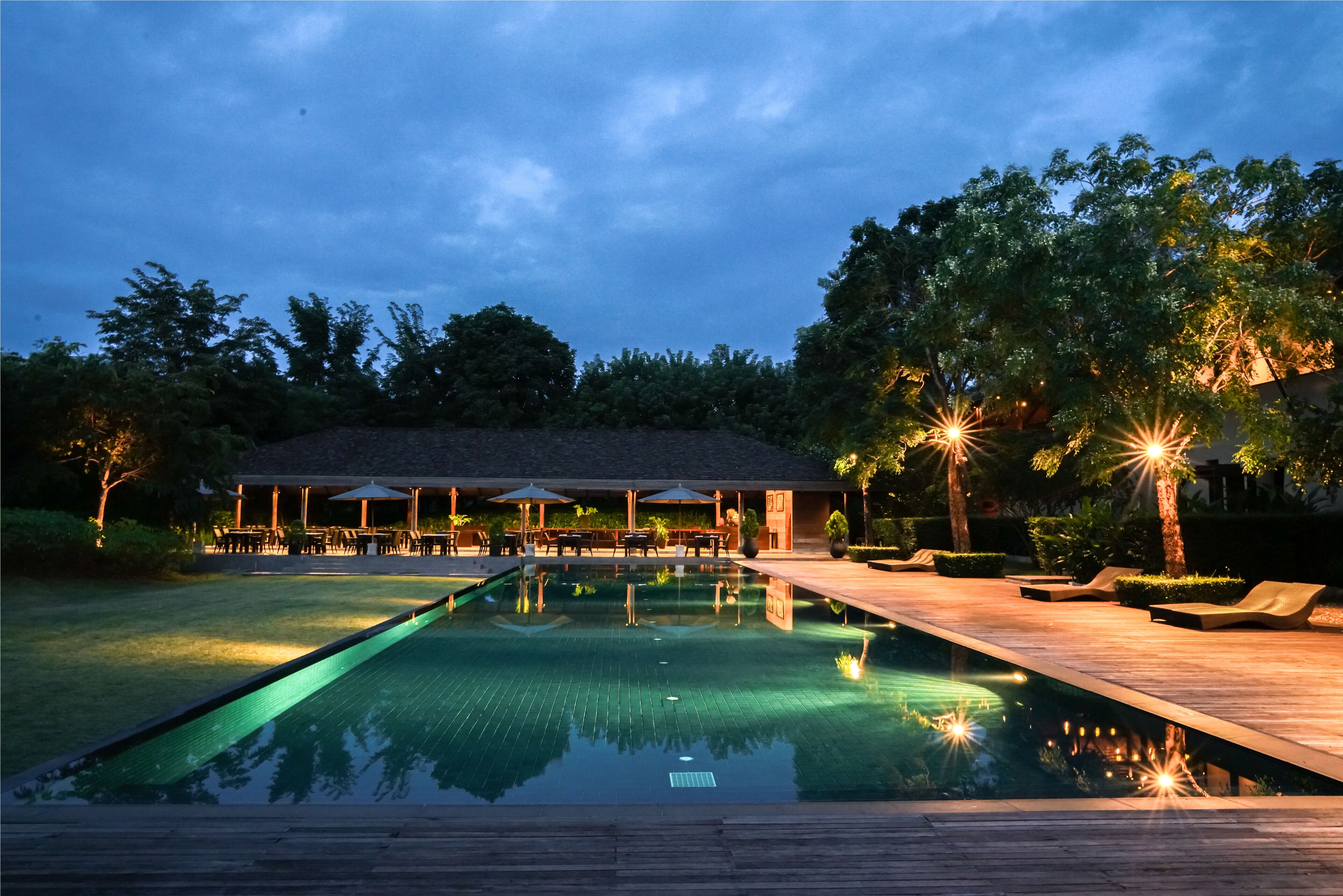 Une piscine avec une terrasse en bois, des chaises longues et des parasols.