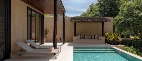 A modern outdoor pool area with lounge chairs and a built-in seating area.