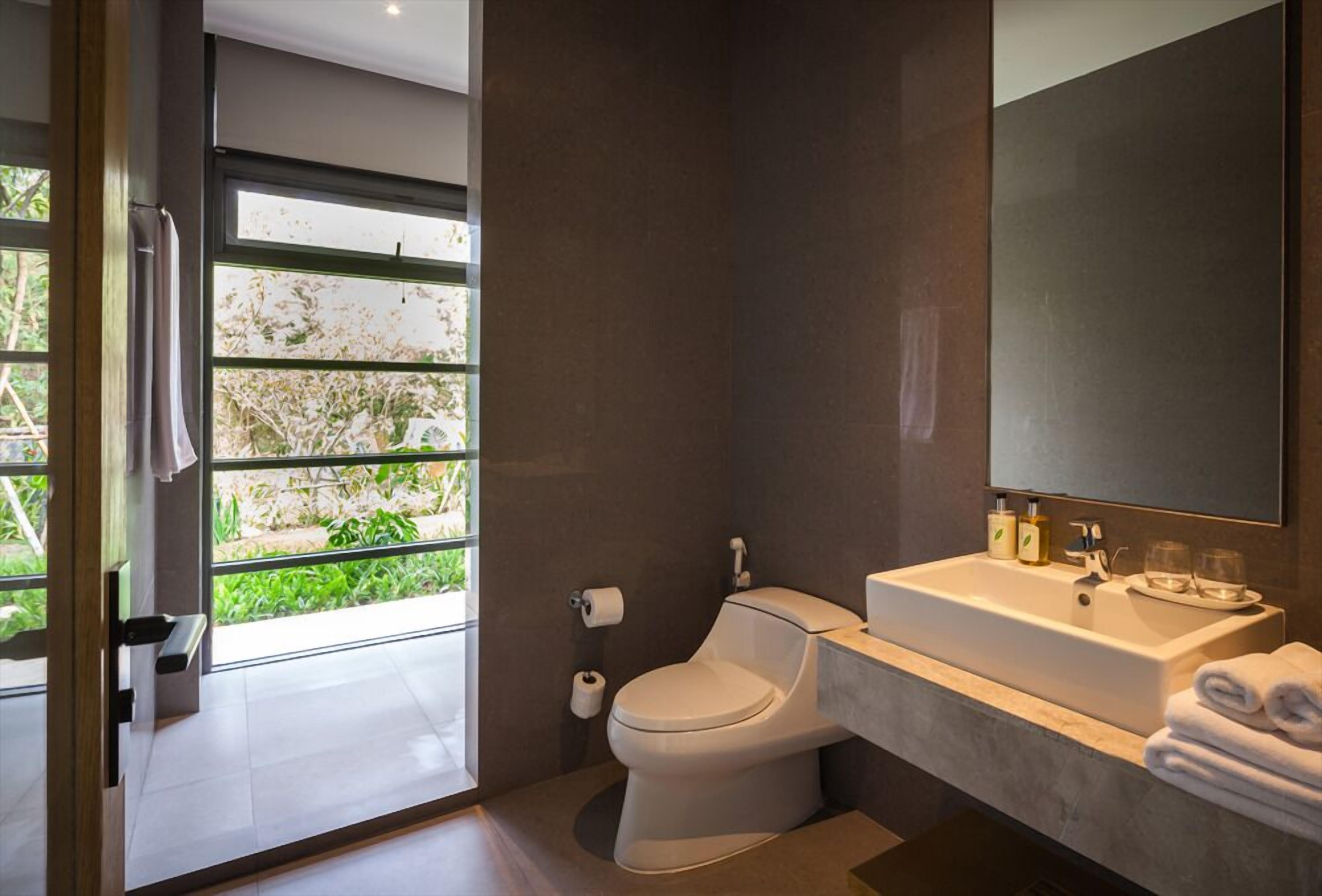 Een moderne badkamer met toilet, wastafel en grote spiegel.