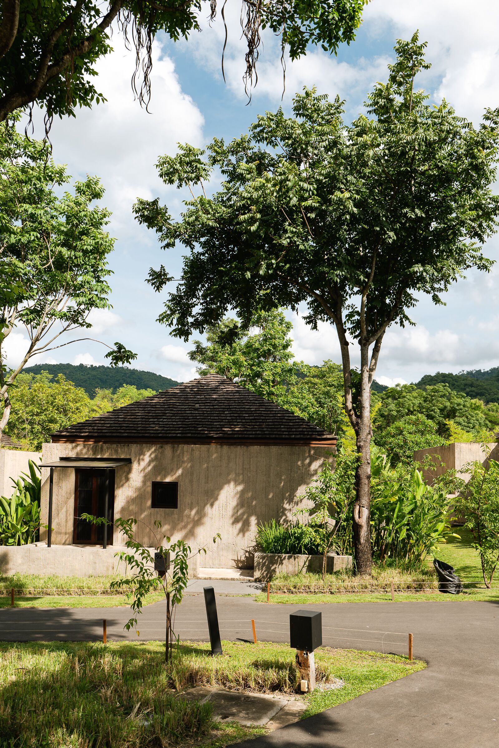 A small building with a tiled roof, surrounded by lush greenery and a clear sky.