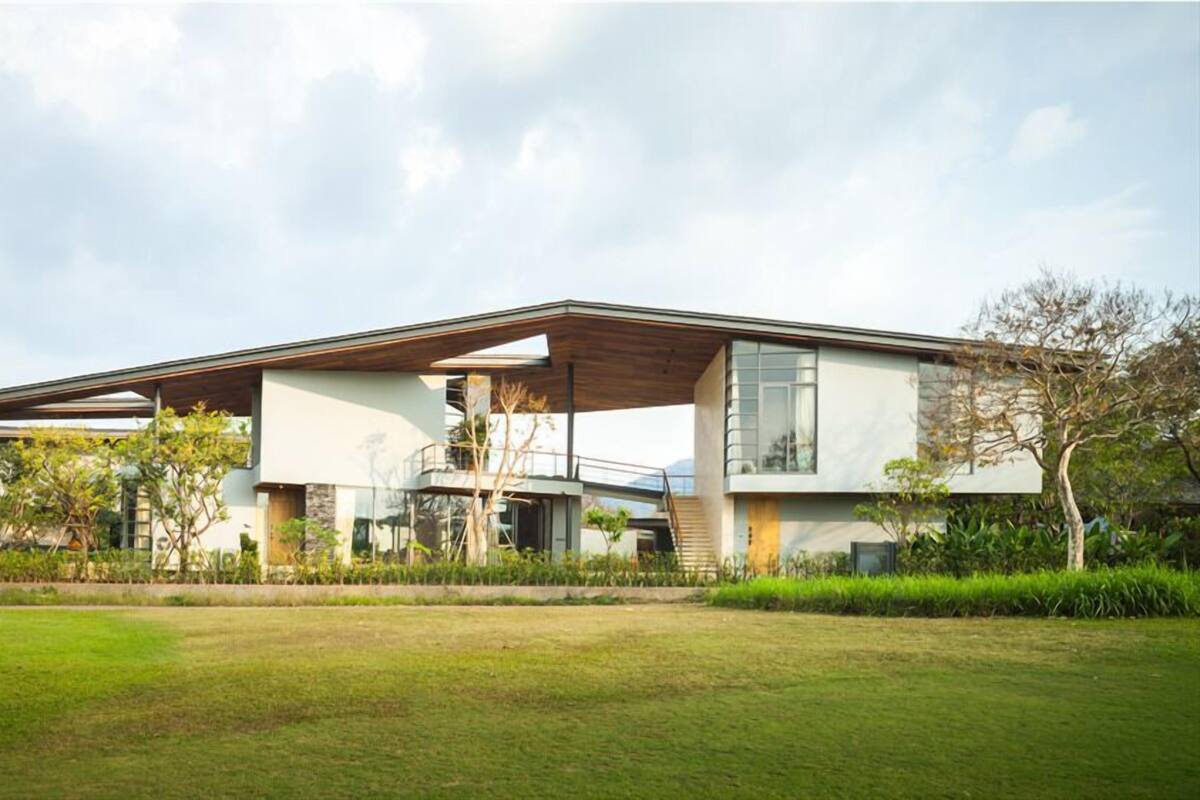 Una casa moderna con techo plano, ventanas amplias y un área exterior cubierta.