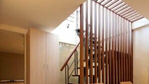 Un interior moderno con una escalera de madera, sillas de mimbre y vistas al exterior.