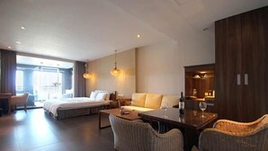 Una habitación de hotel moderna con una cama grande, un sofá, una mesa de comedor y un espacio de estar.