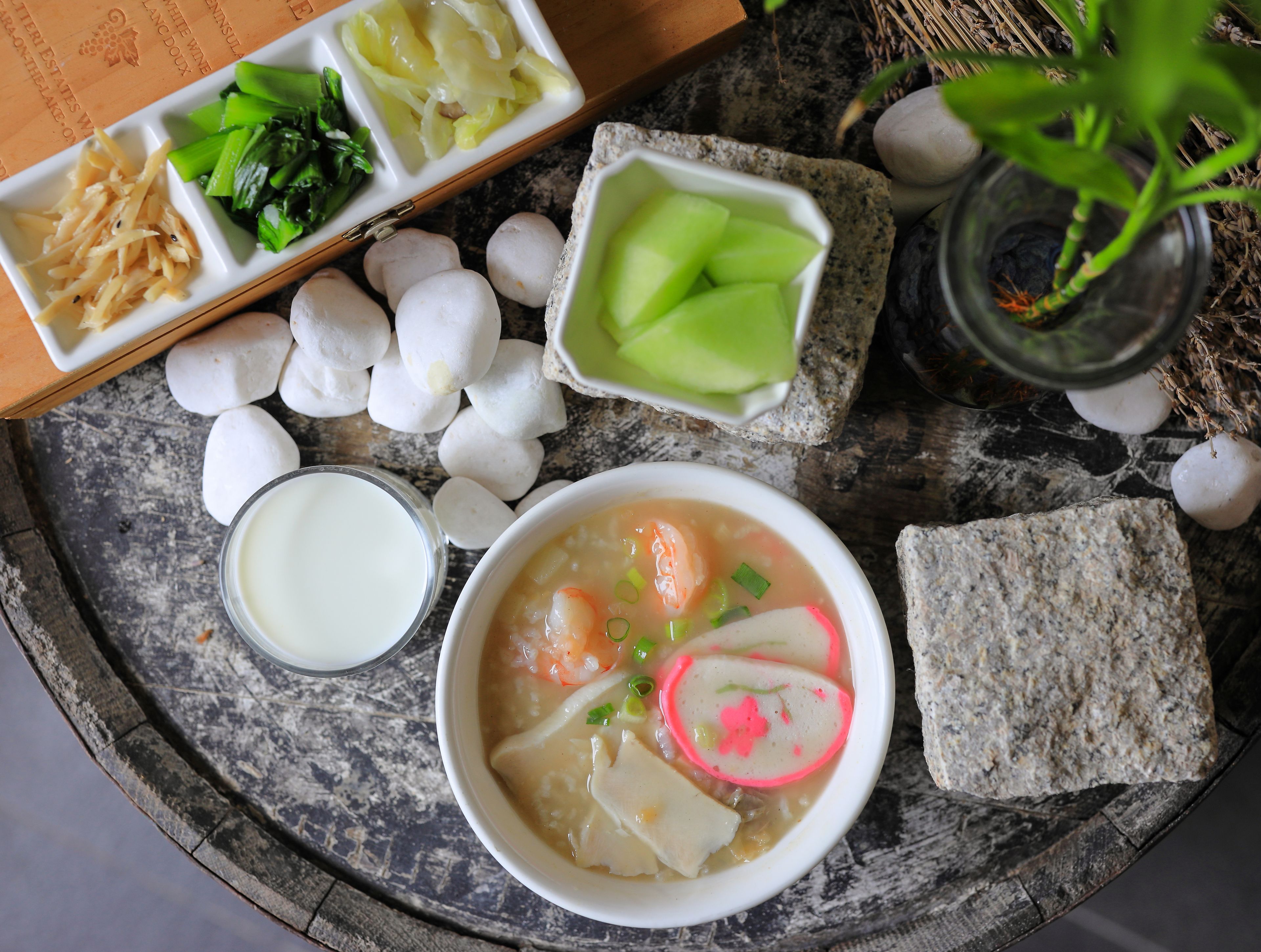 A meal with various dishes including a bowl of soup, a plate of vegetables, and a glass of milk.