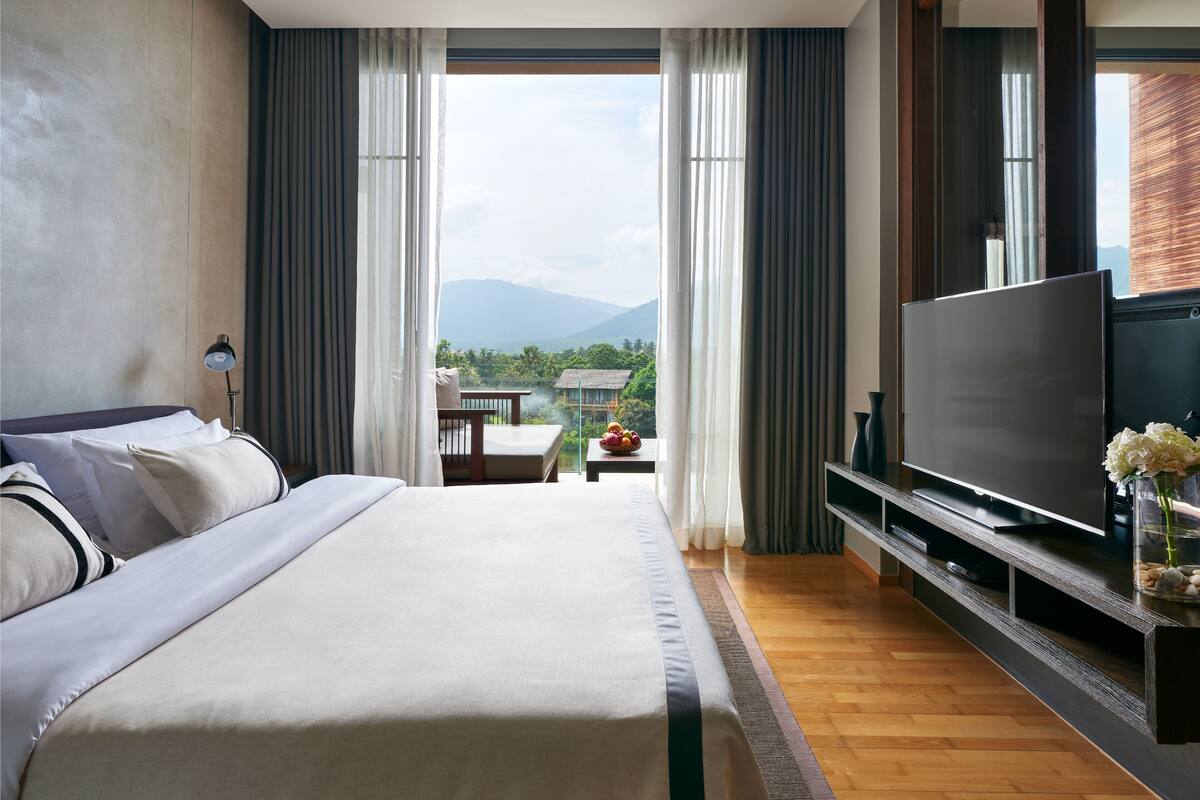 A hotel room with a large bed, a flat-screen TV, and a view of the outdoors.