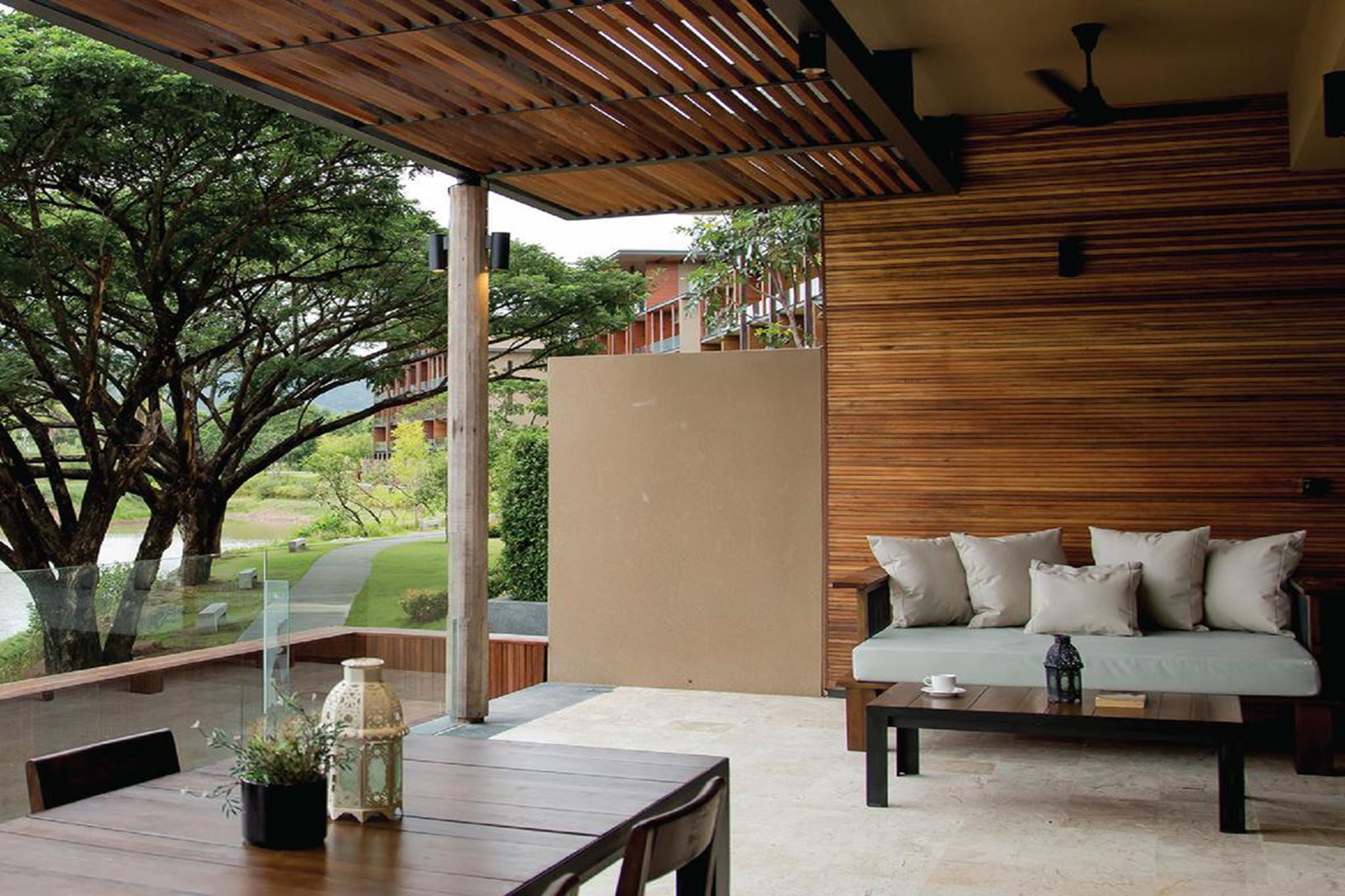 Un espace extérieur moderne, aménagé avec un plafond en bois et une paroi vitrée donnant sur un jardin.