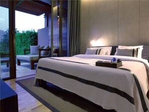 Una camera d'hotel moderna con un ampio letto, un piccolo angolo relax e vista sul verde.